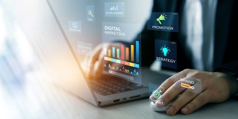 In the background is a closeup of a blurry laptop and someone in a suit’s hands on the keyboard. Hovering over the keyboard are graphics that say: Digital Marketing, Promotion, Strategy, Brand, Target, Social Media, Advertising, SEO, Development