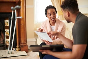 Women on couch discussing bills with a young man.