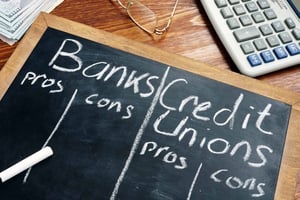 Chalkboard with some Pros and Cons of Banks versus Credit Unions written on it.