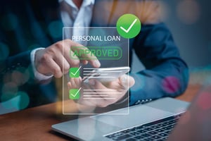 A close-up on the arms and hands of a man in a suit, using a smartphone. Superimposed is a transparent image with a green checkmark that says: Personal Loan Approved. 