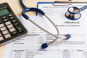A table with a calculator and medical bills stacking up