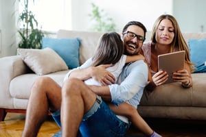 Happy family relaxing on couch will on a tablet device.