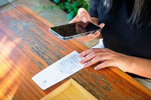 Woman taking a photo of a receipt as a way to track her expenses.