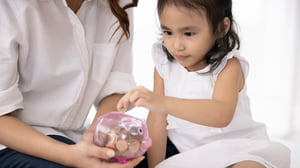Single mom and child saving money with a piggy bank