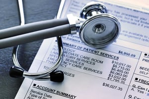 A close up of a printed-out medical bill, each service costing thousands of dollars, with a stethoscope sitting on top of the paper.